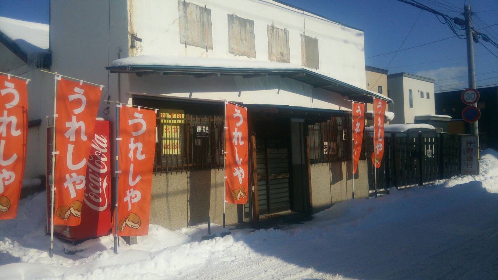 雪の日の店の外観。赤いのぼりが並ぶ
