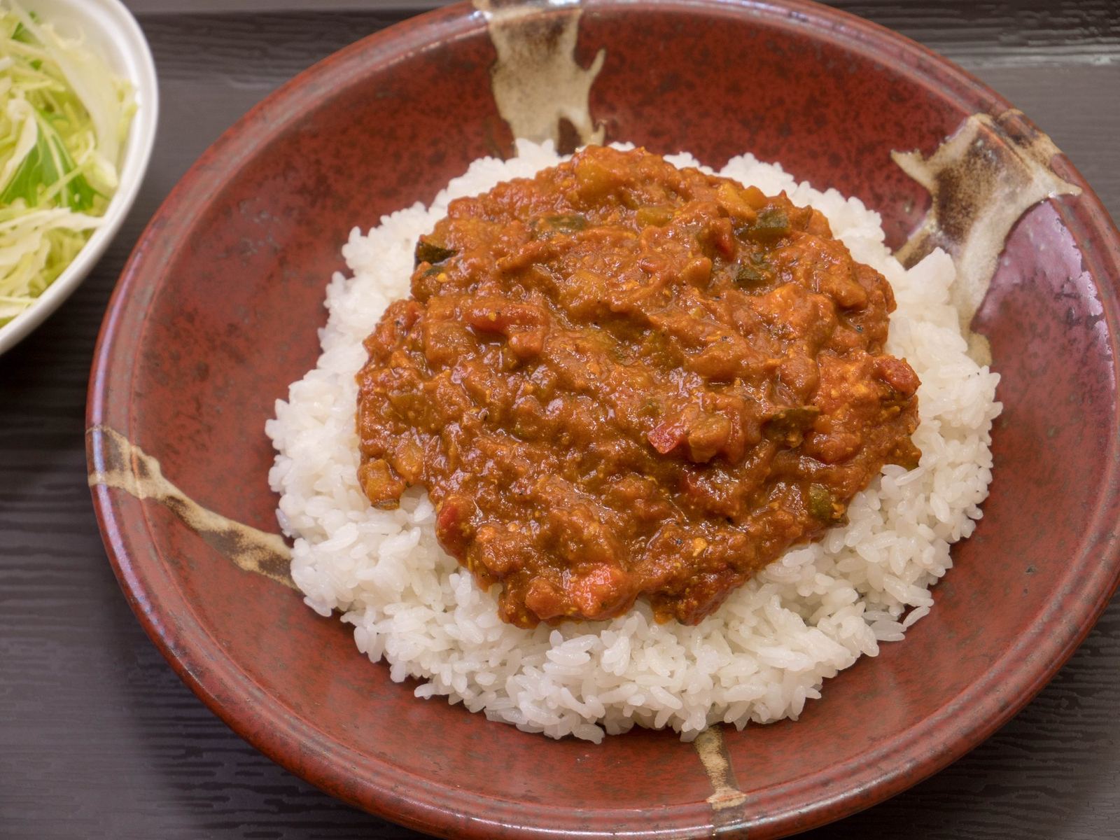 赤茶の器に盛ったキーマカレー。ご飯の上にひき肉と野菜のカレー