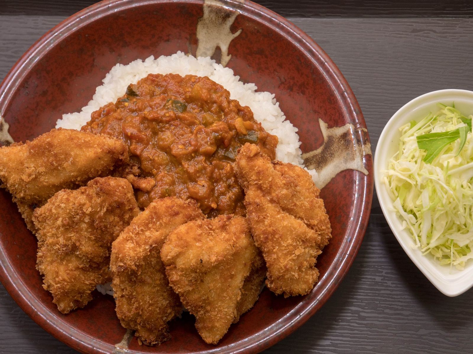 キーマカレーの上にチキンカツを並べた丼と、千切りキャベツの小鉢