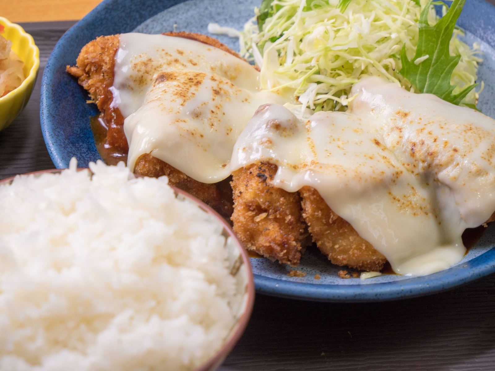 デミグラスソースとチーズをかけたチキンカツ。千切りキャベツとご飯
